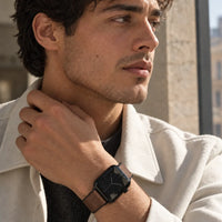 Mann im hellen Mantel trägt das Aura Leder Apple Watch Armband in Schwarz